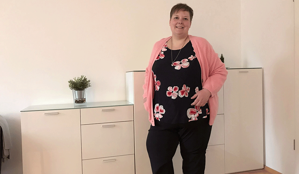 Britta mit schwarzer Hose, Blumen-Shirt und rosa Strickjacke