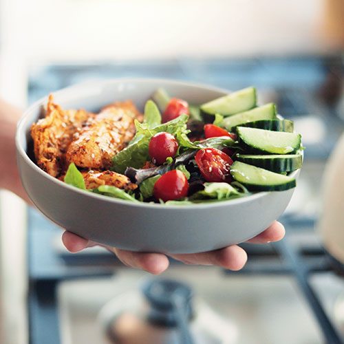 Bowl mit grünem Gemüse, Tomaten und Fisch