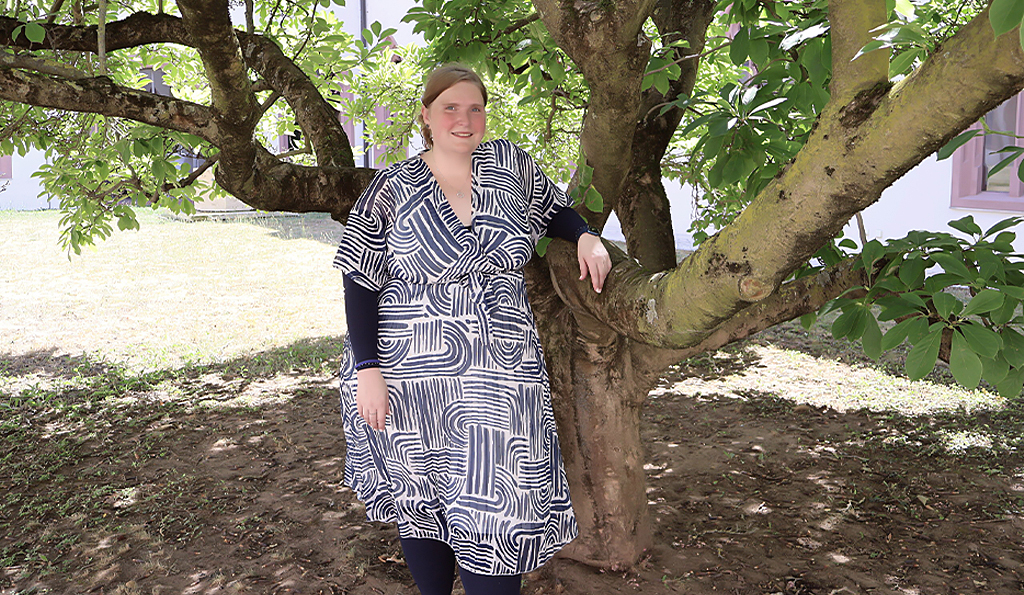 Sabine mit blauem Kleid vor einem Baum
