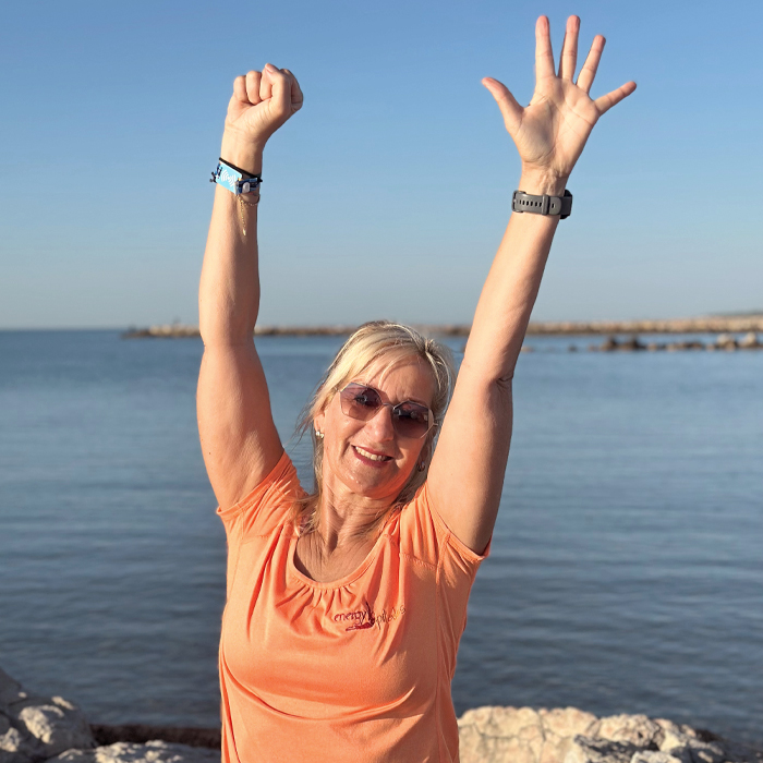 Michaela am Meer und streckt die Hände hoch