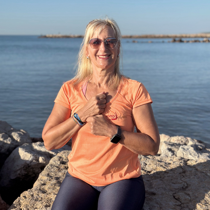 Michaela sitzt am Meer auf einem Stein